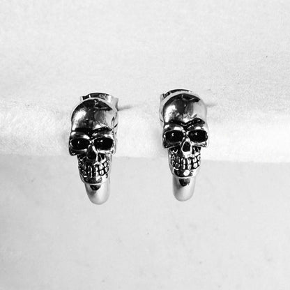 Silver skull earrings facing forward.