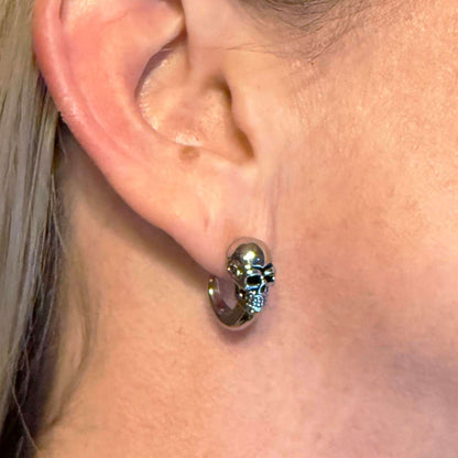 Lady wearing silver skull earring on ear, close up.